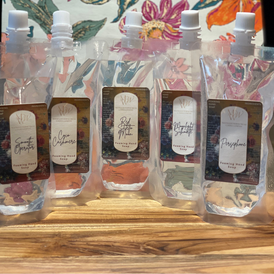 Close up image of Foaming Handsoap Refills on a wooden surface with a floral background