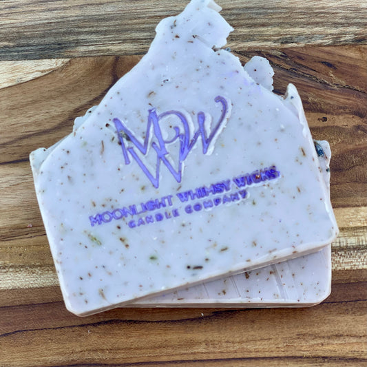 Close-up of Moonlight Whimsy Wicks handmade lavender soap bar with purple logo, cold processed and infused with natural botanicals and exfoliating herbs. Artisan soap for sensitive skin, crafted in small batches for natural skincare routines