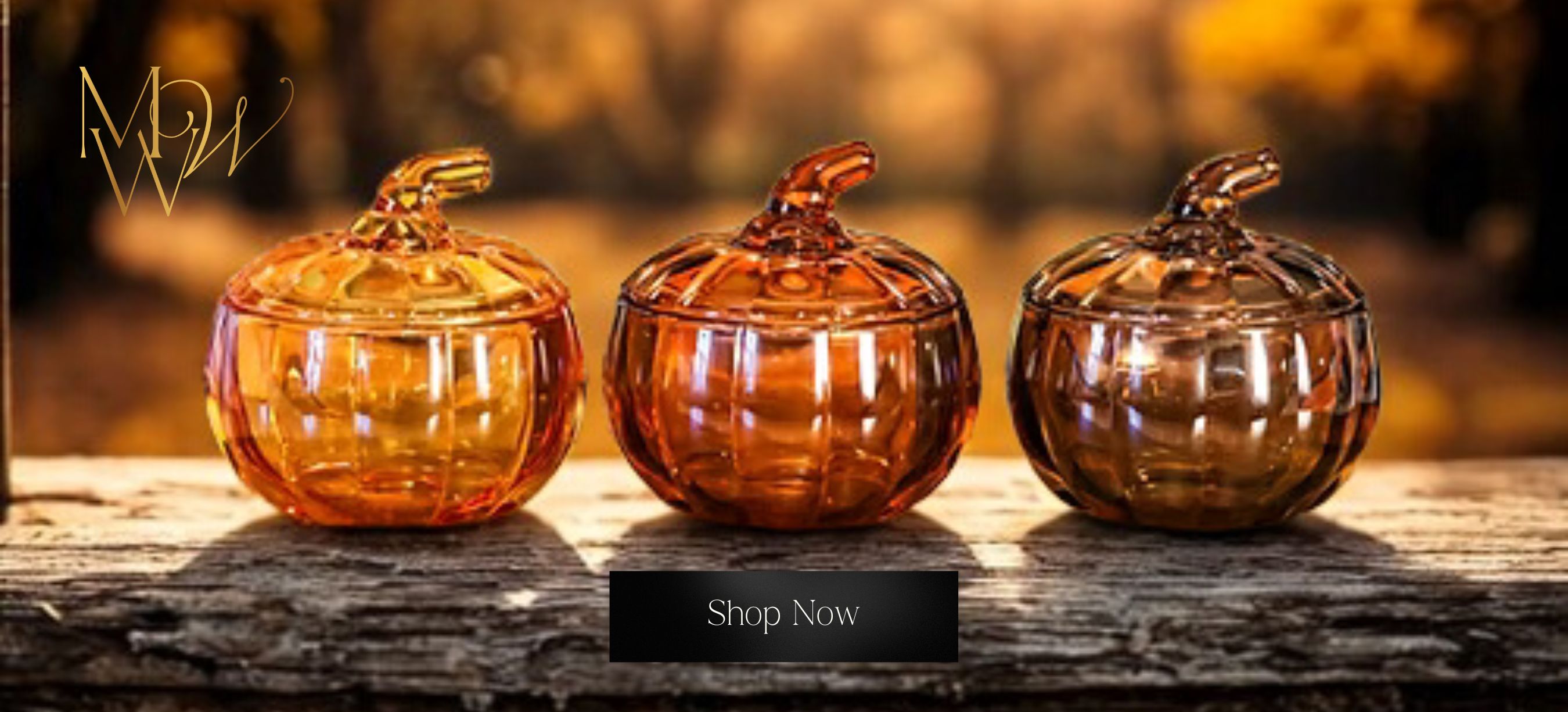 Three amber-colored glass pumpkin containers on a wooden surface with a blurred natural background.