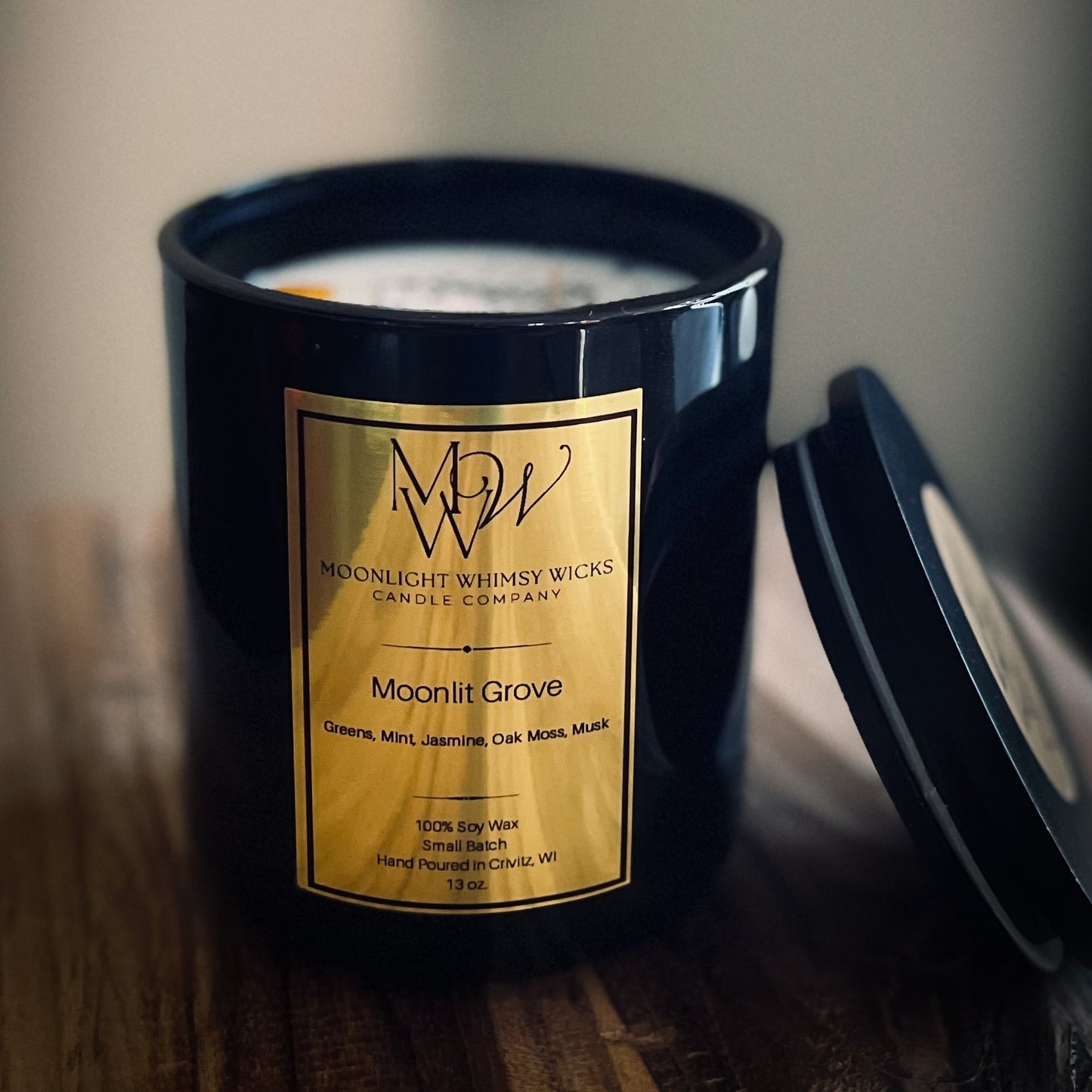 Candle scene featuring Moonlit Grove in a black glossy vessel, a woodsy fresh candle with eucalyptus and moss notes, cozy sweater season vibe inspired by BBW Sweater Weather.
