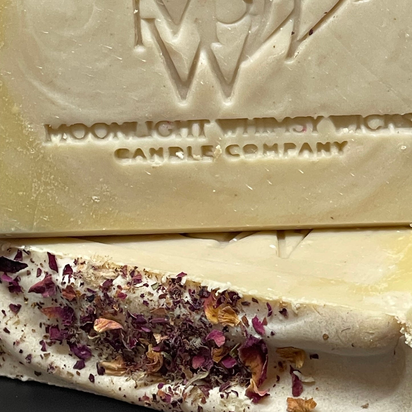 Bar of soap with dried flowers and Moonlight Manna Candle Company branding.