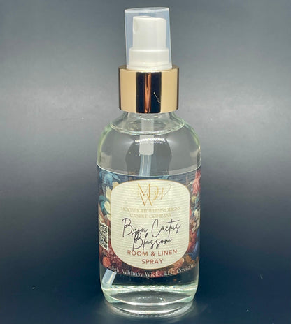Clear spray bottle with gold cap labeled 'Baja Cactus Blossom' on a dark background from Moonlight Whimsy Wicks