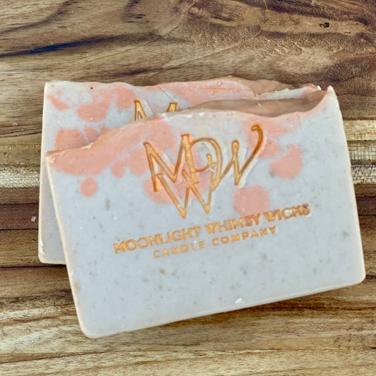 Moonlight Whimsy Wicks handmade artisan soap bar with warm orange swirls and gold foil logo, crafted using the cold process method. Small batch natural soap with a soft citrus scent and gentle exfoliating texture, ideal for daily skincare.  Inspired by Bitter Peach.