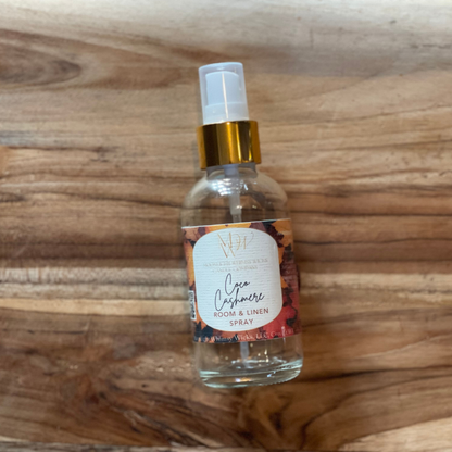 Room & Linen spray bottle labeled 'Coco Cashmere by Moonlight Whimsy Wicks on a wooden surface
