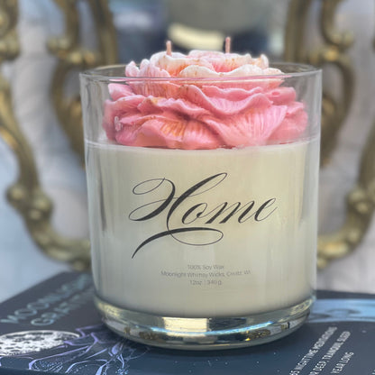 Candle with pink rose in a glass container on top of books,
