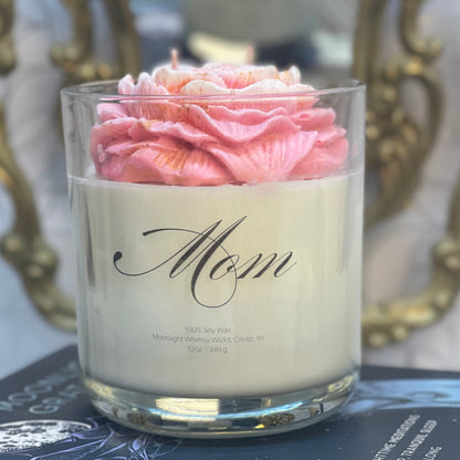Candle with pink peony in a glass holder on top of books, with decorative background