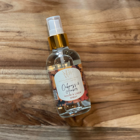 Room spray bottle labeled 'Oakmoss & Amber' on a wooden surface