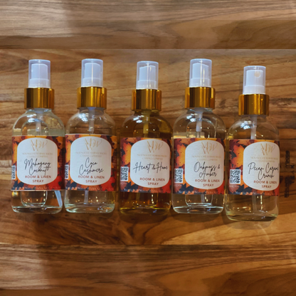 Five glass spray bottles with gold caps on a wooden surface