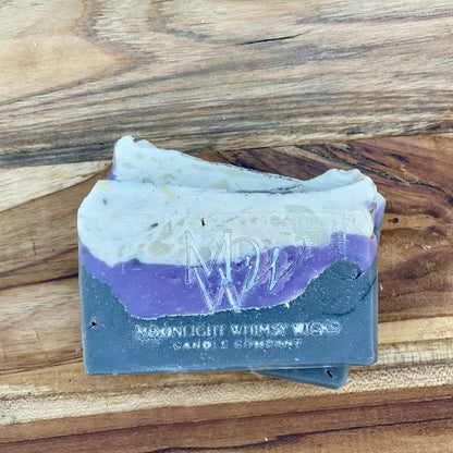 Moonlight Whimsy Wicks artisan soap bar with dramatic layers of charcoal black, lavender purple, and creamy white. Handmade cold processed soap.