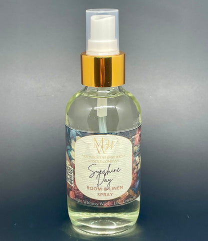 Clear spray bottle with gold cap labeled 'Sunshine Day Room & Linen Spray' on a gray background