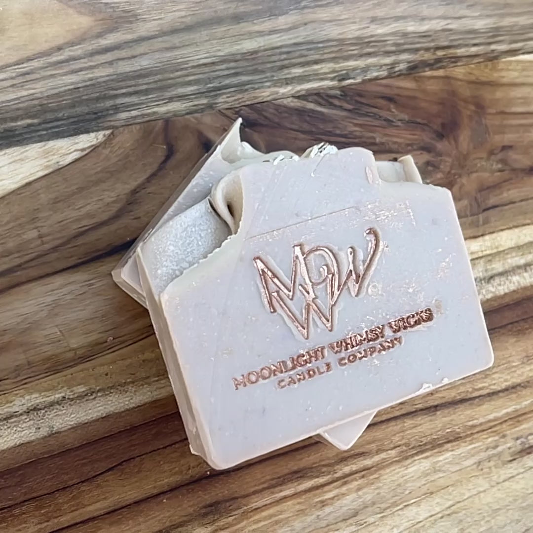 Short, close up video of Moonlight Whimsy Wicks handmade Oatmeal Milk & Honey cold process soap bar, embossed with a copper foil logo. Small batch artisan soap made with nourishing oils, oatmeal, and a warm comforting scent for dry and sensitive skin.