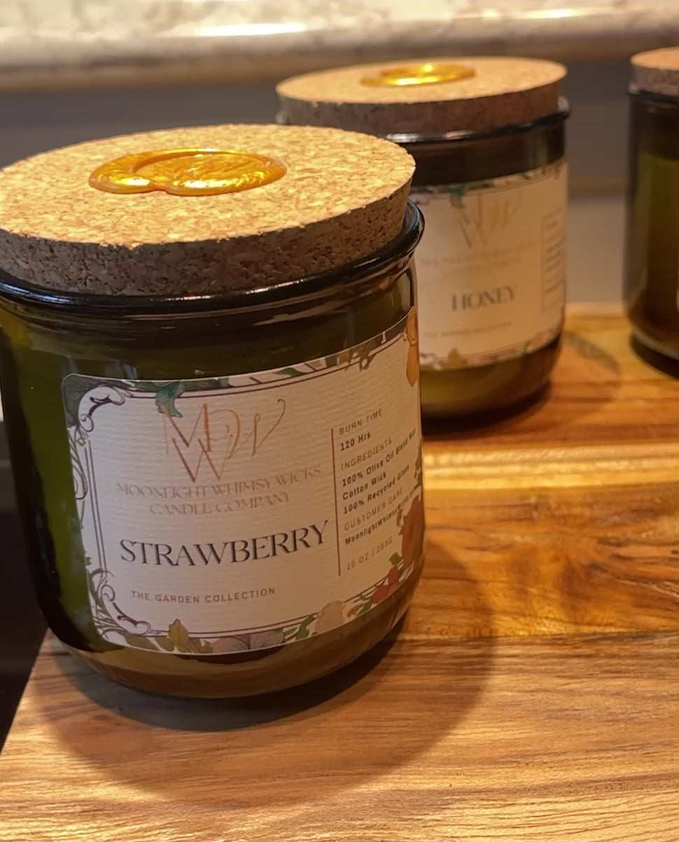 Video showcasing the Heirloom Tomato, Honey, Thyme, Lemongrass, Peaches and Strawberry Candles from Moonlight Whimsy Wicks' Garden Collection. Features the eco-luxury candle in a heritage green glass vessel with creamy olive oil wax and a cork lid sealed in gold wax, surrounded by garden-fresh tomatoes and herbs. Ideal for lovers of sustainable, botanical-inspired home fragrance.