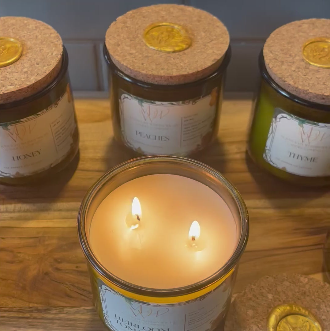 Video showcasing the Heirloom Tomato, Honey, Thyme, Lemongrass, Peaches and Strawberry Candles from Moonlight Whimsy Wicks' Garden Collection. Features the eco-luxury candle in a heritage green glass vessel with creamy olive oil wax and a cork lid sealed in gold wax, surrounded by garden-fresh tomatoes and herbs. Ideal for lovers of sustainable, botanical-inspired home fragrance.
